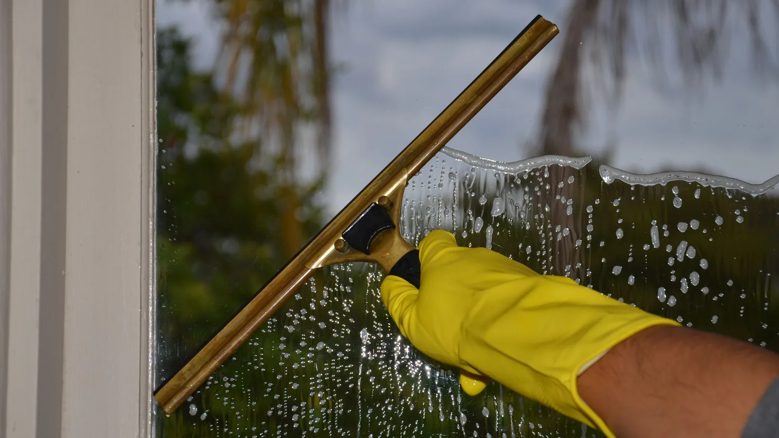 Fensterreinigung mit Abzieher an einer nassen Glasscheibe